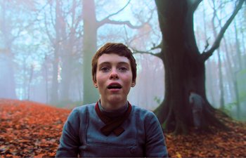 Movie still from “Gretel & Hansel” (2020), directed by Oz Perkins – A young boy in a blue shirt and a red bow tie; Medium shot, Low angle