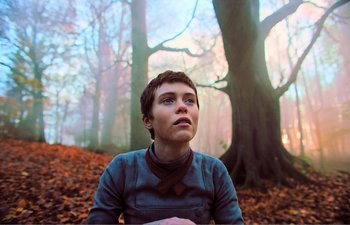 Movie still from “Gretel & Hansel” (2020), directed by Oz Perkins – A woman sitting in front of a tree in the woods; Close Up shot, Low angle