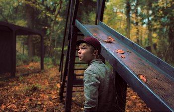Movie still from “Gretel & Hansel” (2020), directed by Oz Perkins – A young man standing in a forest holding a wooden platform; Wide shot, Low angle