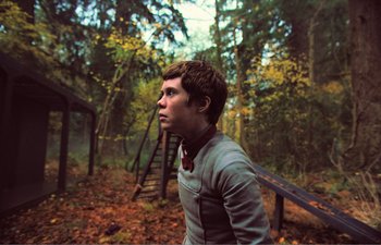 Movie still from “Gretel & Hansel” (2020), directed by Oz Perkins – A young man standing in the middle of a forest; Medium shot, Low angle