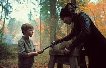 Movie still from “Gretel & Hansel” (2020), directed by Oz Perkins – A woman and a boy working on a wooden object; Medium shot, Over the shoulder angle