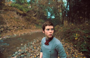 Movie still from “Gretel & Hansel” (2020), directed by Oz Perkins – A young boy standing in a wooded area near a stream; Close Up shot, Low angle