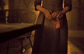 Movie still from “Gretel & Hansel” (2020), directed by Oz Perkins – A woman in an old - fashioned dress is holding a napkin; Medium shot, High angle