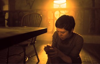 Movie still from “Gretel & Hansel” (2020), directed by Oz Perkins – A man sitting on the floor looking at his cell phone; Medium shot, Low angle