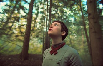 Movie still from “Gretel & Hansel” (2020), directed by Oz Perkins – A young man looking up into the sky in the woods; Close Up shot, Low angle