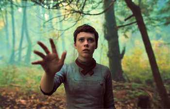 Movie still from “Gretel & Hansel” (2020), directed by Oz Perkins – A person in a forest holding their hand up to the camera; Medium shot, Low angle