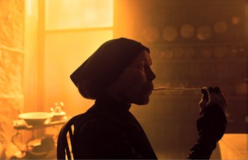 Movie still from “Gretel & Hansel” (2020), directed by Oz Perkins – A man is smoking a pipe in a room; Medium shot, Over the shoulder angle