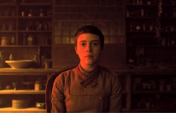 Movie still from “Gretel & Hansel” (2020), directed by Oz Perkins – A person sitting in a chair in a room; Medium shot, Low angle