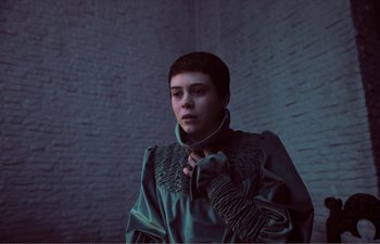 Movie still from “Gretel & Hansel” (2020), directed by Oz Perkins – A woman in a green jacket standing in a room; Medium shot, Low angle