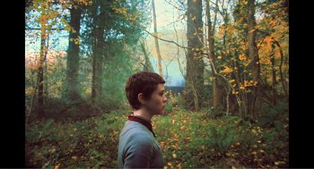 Movie still from “Gretel & Hansel” (2020), directed by Oz Perkins – A young man standing in the middle of a forest; Medium shot, Over the shoulder angle