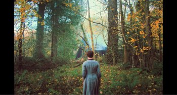 Movie still from “Gretel & Hansel” (2020), directed by Oz Perkins – A woman in a dress standing in the woods; Wide shot, Over the shoulder angle