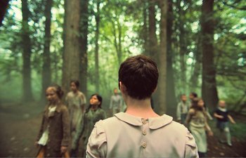 Movie still from “Gretel & Hansel” (2020), directed by Oz Perkins – A group of people standing in the woods; Wide shot, Over the shoulder angle