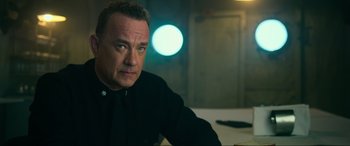 Movie still from “Greyhound” (2020), directed by Aaron Schneider – A man sitting in front of a table with lights in the background; Close Up shot, Over the shoulder angle