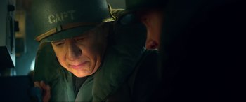 Movie still from “Greyhound” (2020), directed by Aaron Schneider – A man wearing a green hat and a green jacket; Close Up shot, Low angle