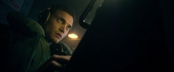 Movie still from “Greyhound” (2020), directed by Aaron Schneider – A young man looking at a laptop computer screen; Close Up shot, Low angle