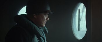 Movie still from “Greyhound” (2020), directed by Aaron Schneider – A man wearing a black hat and a green jacket; Close Up shot, Over the shoulder angle