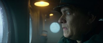 Movie still from “Greyhound” (2020), directed by Aaron Schneider – A person wearing a hat looking out a window; Close Up shot, Low angle