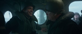 Movie still from “Greyhound” (2020), directed by Aaron Schneider – Two men in military uniforms are talking in a plane; Medium shot, Over the shoulder angle