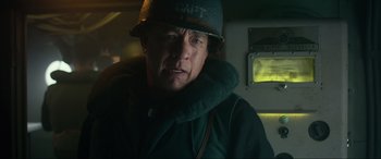 Movie still from “Greyhound” (2020), directed by Aaron Schneider – A man wearing a hat and a neck brace; Close Up shot, Low angle