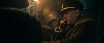 Movie still from “Greyhound” (2020), directed by Aaron Schneider – A man talking on a phone next to another man; Close Up shot, Low angle