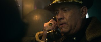 Movie still from “Greyhound” (2020), directed by Aaron Schneider – A man in a hat is talking on a phone; Close Up shot, Low angle