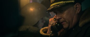 Movie still from “Greyhound” (2020), directed by Aaron Schneider – A man in a military uniform talking on a phone; Close Up shot, Low angle