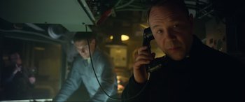 Movie still from “Greyhound” (2020), directed by Aaron Schneider – A man holding a phone up to his ear while standing next to another man; Close Up shot, High angle