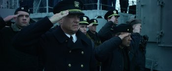 Movie still from “Greyhound” (2020), directed by Aaron Schneider – A group of men in uniform saluting in front of a ship; Medium shot, Low angle