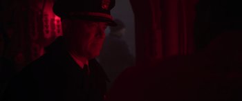 Movie still from “Greyhound” (2020), directed by Aaron Schneider – A man wearing a uniform and a hat is in the dark; Close Up shot, Over the shoulder angle