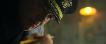 Movie still from “Greyhound” (2020), directed by Aaron Schneider – A person wearing a hat and holding a pencil; Close Up shot, Low angle