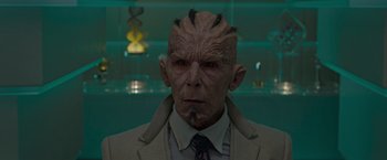 Movie still from “Guardians of the Galaxy” (2014), directed by James Gunn – A man in a suit and tie with a strange face; Close Up shot, Over the shoulder angle