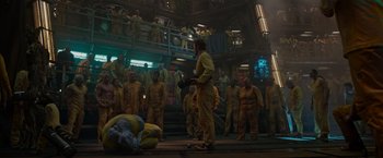 Movie still from “Guardians of the Galaxy” (2014), directed by James Gunn – A group of people in yellow suits standing in a room; Extreme Wide shot, Over the shoulder angle