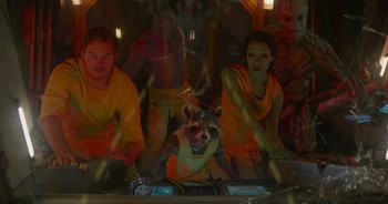 Movie still from “Guardians of the Galaxy” (2014), directed by James Gunn – A group of people in a room with a racoon mask on; Medium shot, Over the shoulder angle