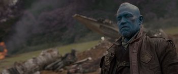 Movie still from “Guardians of the Galaxy” (2014), directed by James Gunn – A man with blue hair and a blue face standing in front of a ship; Medium shot, Over the shoulder angle