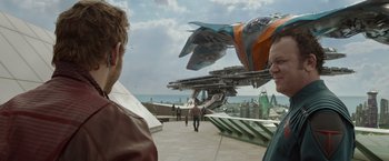 Movie still from “Guardians of the Galaxy” (2014), directed by James Gunn – Two people are walking on a sidewalk near a building; Wide shot, Over the shoulder angle