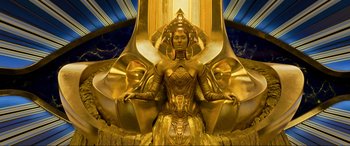 Movie still from “Guardians of the Galaxy Vol. 2” (2017), directed by James Gunn – A woman sitting in a chair in a gold dress; Wide shot, Overhead angle