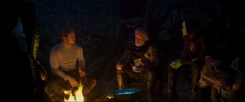 Movie still from “Guardians of the Galaxy Vol. 2” (2017), directed by James Gunn – A man sitting next to a fire in the woods; Medium shot, Over the shoulder angle