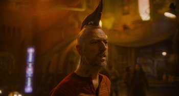Movie still from “Guardians of the Galaxy Vol. 3” (2023), directed by James Gunn – A bald man with a strange hat on his head; Close Up shot, Over the shoulder angle