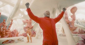 Movie still from “Guardians of the Galaxy Vol. 3” (2023), directed by James Gunn – A man in a red suit is raising his hands; Medium shot, Low angle
