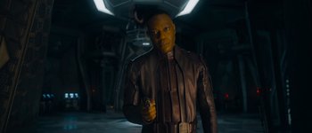 Movie still from “Guardians of the Galaxy Vol. 3” (2023), directed by James Gunn – A man holding a gun while standing in a dark room; Medium shot, Low angle