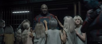 Movie still from “Guardians of the Galaxy Vol. 3” (2023), directed by James Gunn – A group of people standing next to a statue of a man; Medium shot, High angle