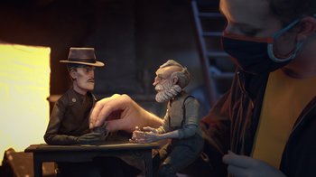 Movie still from “Guillermo del Toro's Pinocchio” (2022), directed by Guillermo del Toro – A man sitting at a table with two other men; Medium shot, Over the shoulder angle