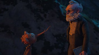 Movie still from “Guillermo del Toro's Pinocchio” (2022), directed by Guillermo del Toro – An old man and a small puppet in a dark room; Medium shot, Over the shoulder angle