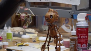 Movie still from “Guillermo del Toro's Pinocchio” (2022), directed by Guillermo del Toro – A wooden statue of groot is sitting on a table; Extreme Close Up shot, High angle