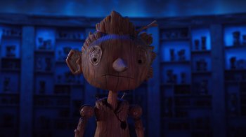 Movie still from “Guillermo del Toro's Pinocchio” (2022), directed by Guillermo del Toro – A wooden doll is standing in front of a bookshelf; Close Up shot, Low angle