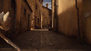 Movie still from “Guillermo del Toro's Pinocchio” (2022), directed by Guillermo del Toro – An alley way with a person sitting on a bench in the distance; Extreme Wide shot, High angle