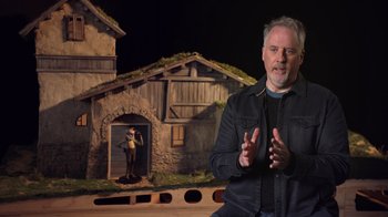 Movie still from “Guillermo del Toro's Pinocchio” (2022), directed by Guillermo del Toro – A man standing in front of an animated scene; Medium shot, Low angle