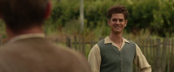 Movie still from “Hacksaw Ridge” (2016), directed by Mel Gibson – A young man in a green vest smiling for the camera; Medium shot, Over the shoulder angle