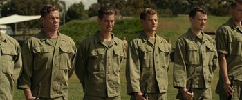 Movie still from “Hacksaw Ridge” (2016), directed by Mel Gibson – A couple of men standing next to each other on top of a grass field; Medium shot, Over the shoulder angle