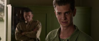 Movie still from “Hacksaw Ridge” (2016), directed by Mel Gibson – A man in a green shirt is looking at the camera; Close Up shot, Over the shoulder angle